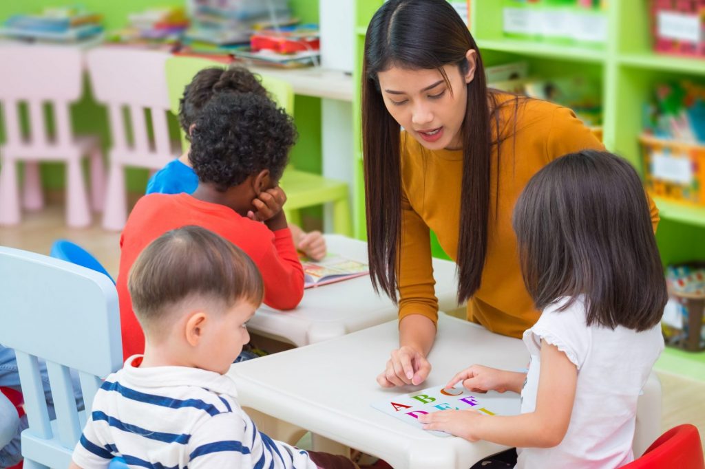 Female educator teaching the alphabet with children.