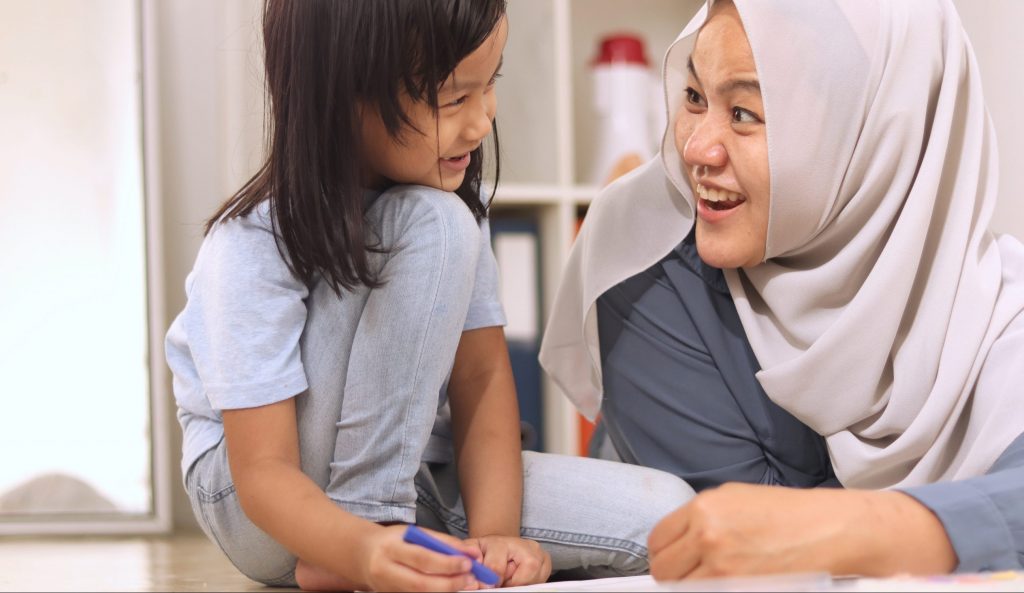 Educatrice coloriant avec un enfant.