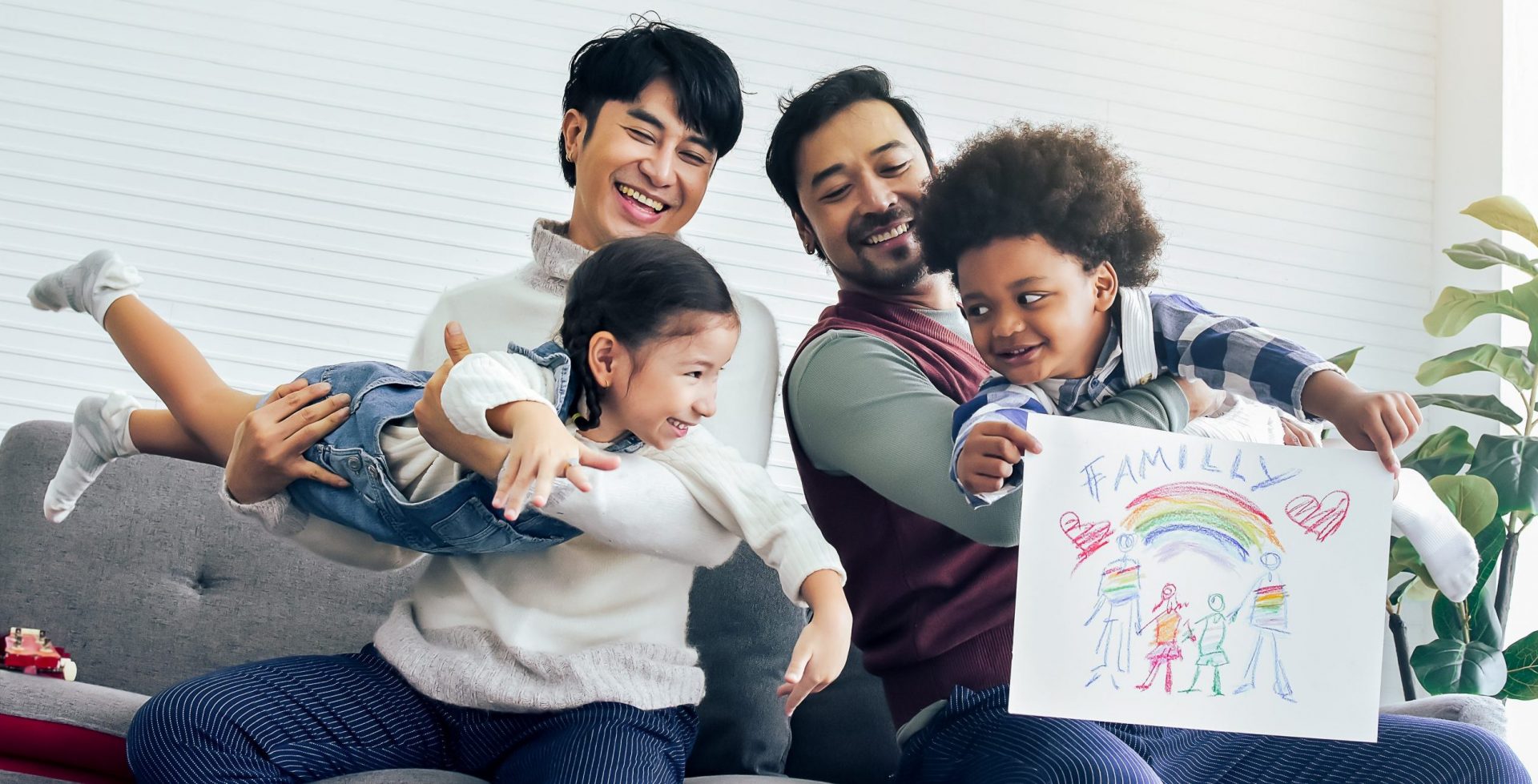 Deux adultes jouant avec des enfants (l'un d'entre eux tient un coloriage).