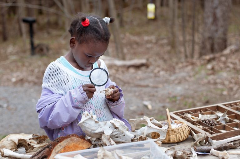 Young Black girl holding magnifying glass.