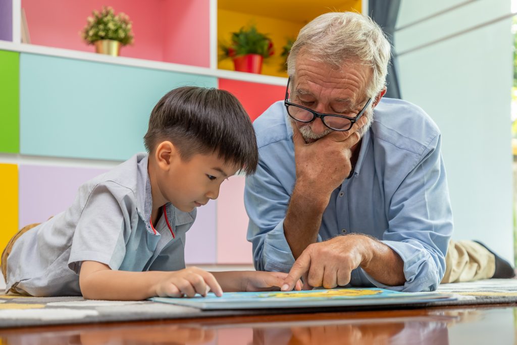 4 year old boy reading with elderly man.