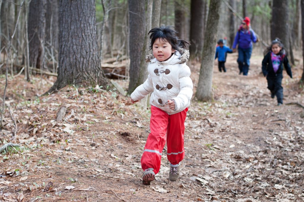 Young Asian girl running in the woods.