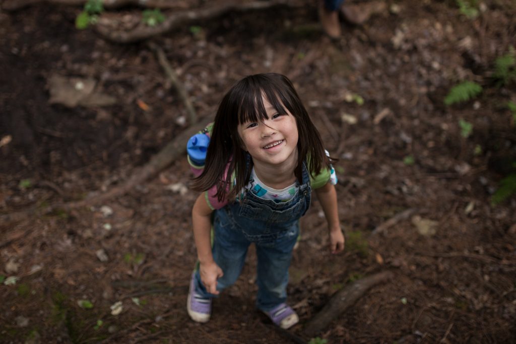 Petite fille qui regarde en haut dans la forêt.