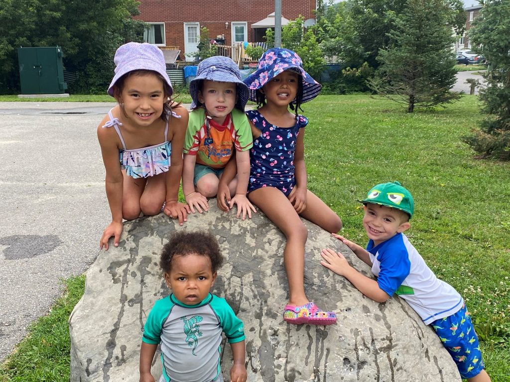 Children in bathing suit chilling on a rock.