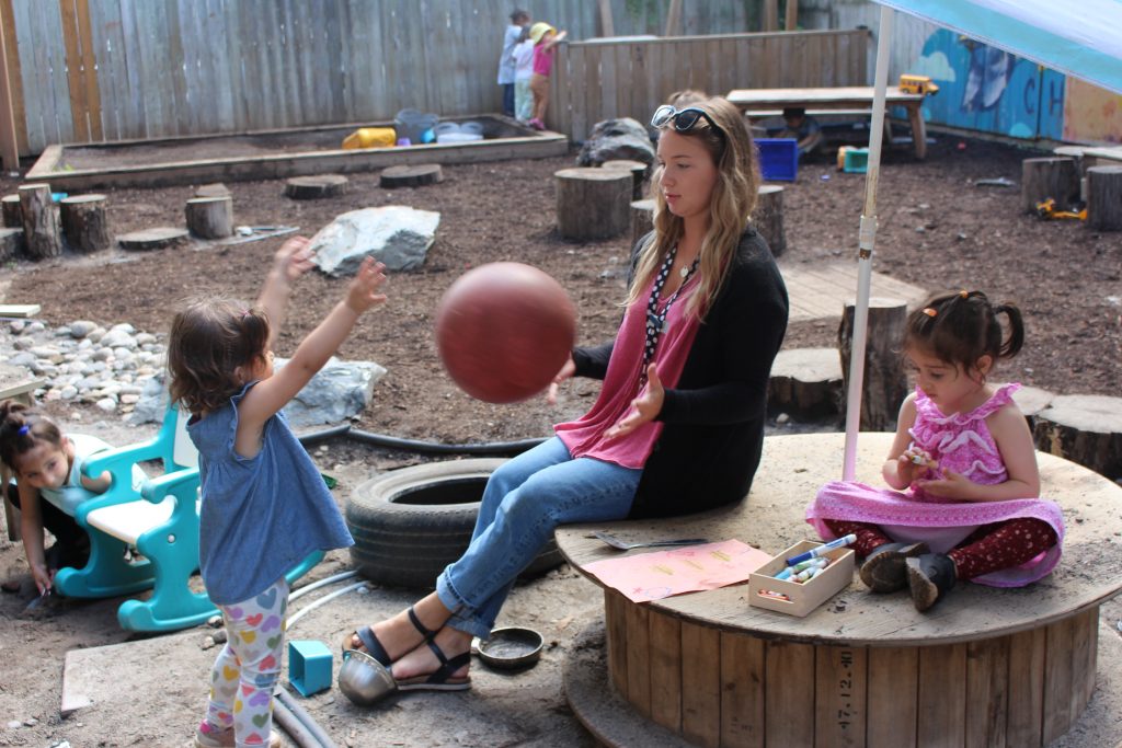 Educator and child playing with ball.