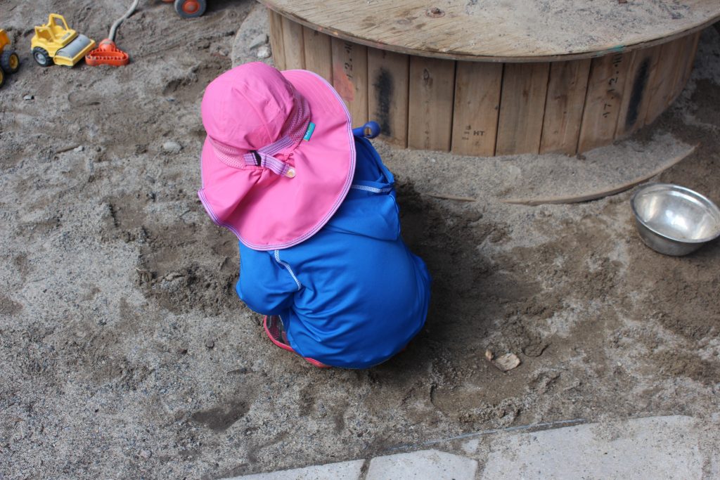 Petite fille au chapeau rose qui joue.