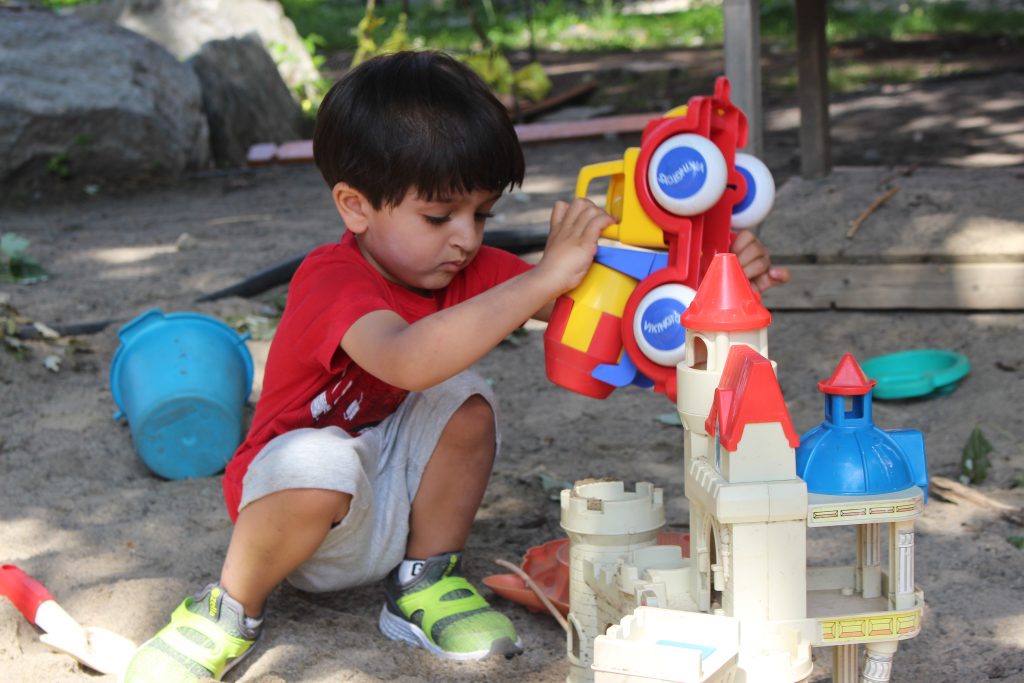 Child playing with truck and castle toy.