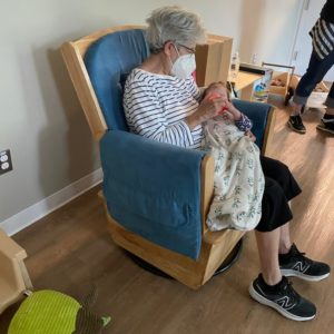 Elderly woman sitting in chair holding a baby.