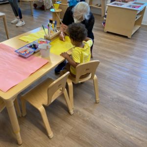 Young boy painting with elderly woman.