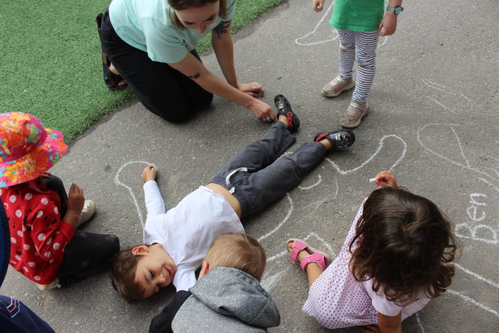 Children playing on ground with chalk.